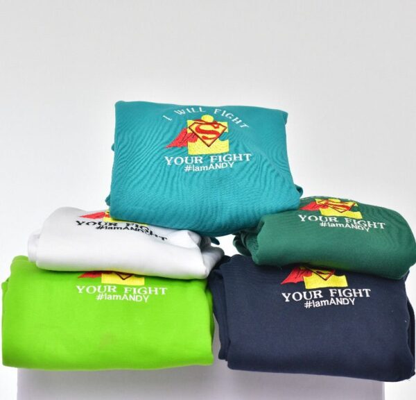 Image of folded hoodies with superman logogs with the text "YOUR Fight #IamAndy"